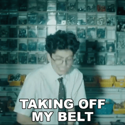 A Man Wearing Glasses And A Tie Says " Taking Off My Belt " GIF