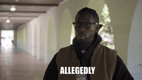 A Man Wearing Glasses And A Vest Has Allegedly Written On His Chest GIF