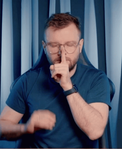 A Man Wearing Glasses And A Watch Is Making A Shhh Gesture GIF