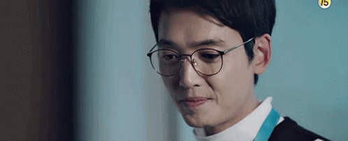 A Man Wearing Glasses And A White Shirt Is Looking Down . GIF