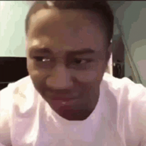 A Man Wearing Glasses And A White Shirt Is Making A Funny Face While Looking At The Camera . GIF