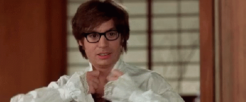 A Man Wearing Glasses And A White Shirt Is Standing In Front Of A Window . GIF