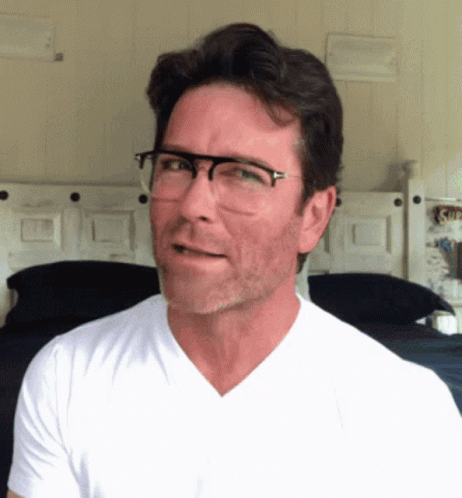 A Man Wearing Glasses And A White Shirt Looks To The Side GIF