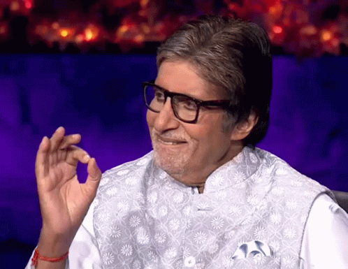 A Man Wearing Glasses And A White Vest Smiles GIF