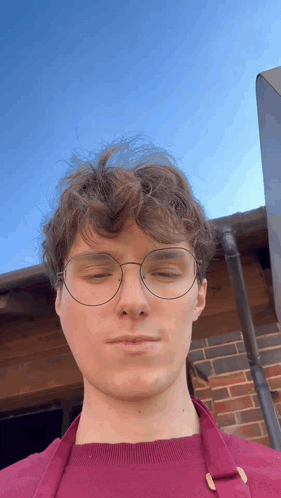 A Man Wearing Glasses And An Apron Looks At The Camera With His Eyes Closed GIF