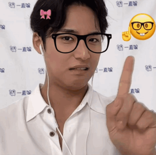 A Man Wearing Glasses And Ear Buds Is Pointing His Finger GIF