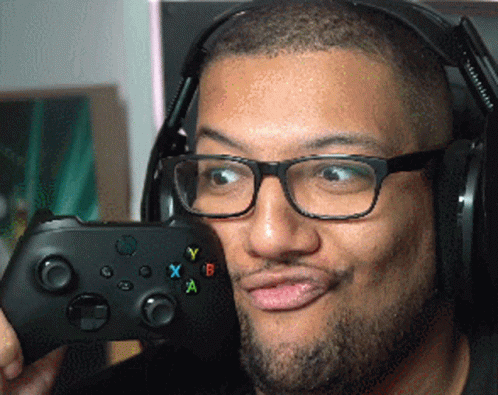 A Man Wearing Glasses And Headphones Is Holding A Controller GIF