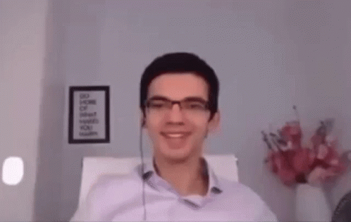 A Man Wearing Glasses And Headphones Is Sitting In A Chair . GIF