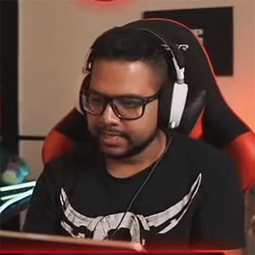 A Man Wearing Glasses And Headphones Is Sitting In A Chair . GIF