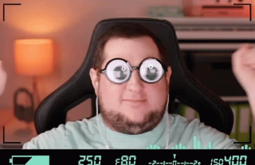 A Man Wearing Glasses And Headphones Is Sitting In A Chair With The Number 250 On The Screen Behind Him GIF