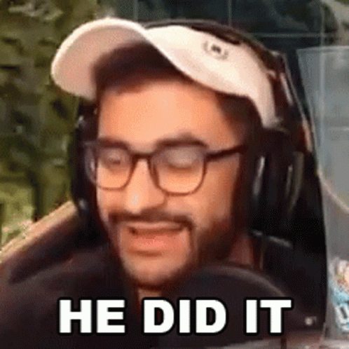 A Man Wearing Glasses And Headphones Is Sitting In Front Of A Microphone And Smiling . GIF