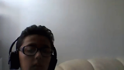 A Man Wearing Glasses And Headphones Looks At The Camera GIF