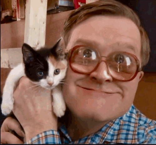 A Man Wearing Glasses Holds A Calico Cat In His Arms GIF