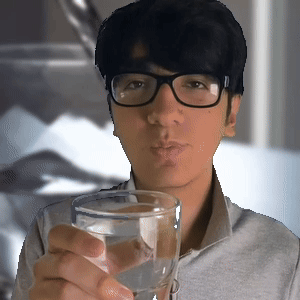 A Man Wearing Glasses Holds A Glass Of Water GIF