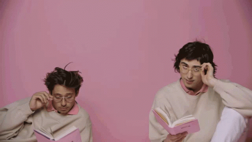 A Man Wearing Glasses Holds A Pink Book That Says ' Poetry ' On It GIF