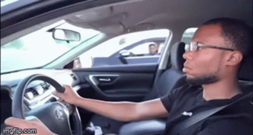 A Man Wearing Glasses Is Driving A Car And Making A Face . GIF
