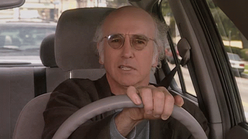 A Man Wearing Glasses Is Driving A Car And Making A Funny Face GIF