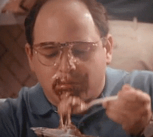 A Man Wearing Glasses Is Eating Spaghetti With A Fork And Spoon . GIF