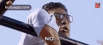 a man wearing glasses is hanging on a bar and says no .
