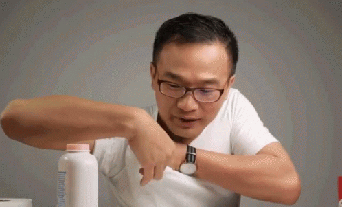 A Man Wearing Glasses Is Holding A Bottle Of Baby Powder In His Pocket GIF