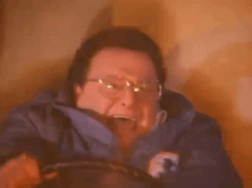 A Man Wearing Glasses Is Holding A Candle In His Hand . GIF
