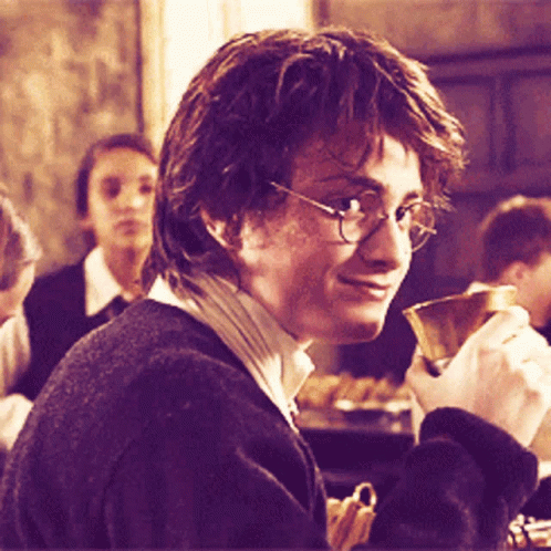 A Man Wearing Glasses Is Holding A Cup In His Right Hand GIF