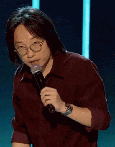 A Man Wearing Glasses Is Holding A Microphone And Says " Good " GIF