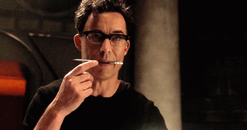 A Man Wearing Glasses Is Holding A Pen In His Mouth GIF