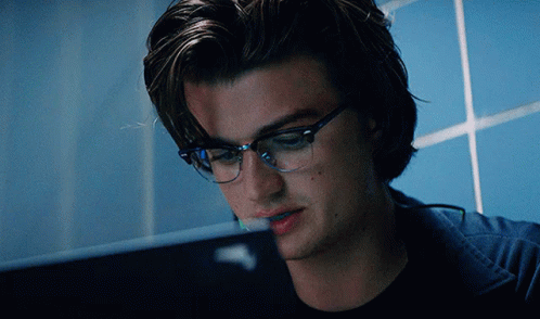 A Man Wearing Glasses Is Looking At A Computer Screen GIF