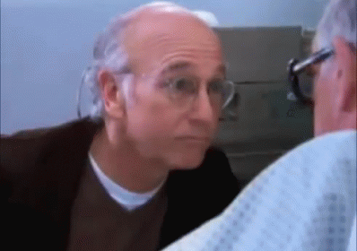 A Man Wearing Glasses Is Looking At Another Man In A Hospital Gown . GIF
