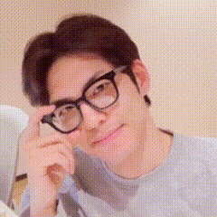 A Man Wearing Glasses Is Looking At The Camera With His Hand On His Face . GIF