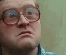 A Man Wearing Glasses Is Making A Funny Face And Looking At The Camera . GIF