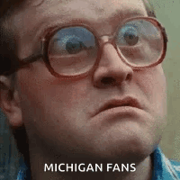A Man Wearing Glasses Is Making A Funny Face With The Words Michigan Fans Written On His Face . GIF