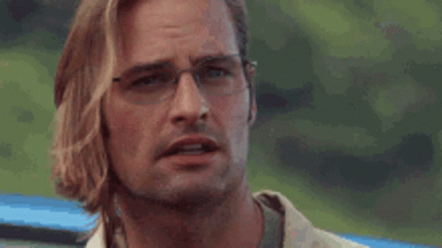 A Man Wearing Glasses Is Scratching His Face . GIF