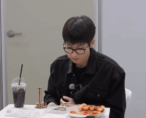 A Man Wearing Glasses Is Sitting At A Table With A Plate Of Food GIF