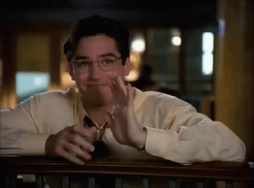 A Man Wearing Glasses Is Sitting At A Table With His Hand On His Face . GIF
