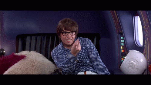 A Man Wearing Glasses Is Sitting On A Couch And Smiling GIF