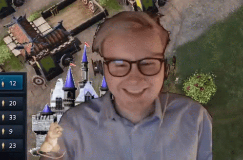 A Man Wearing Glasses Is Smiling In Front Of A Video Game Screen With The Number 12 On It GIF
