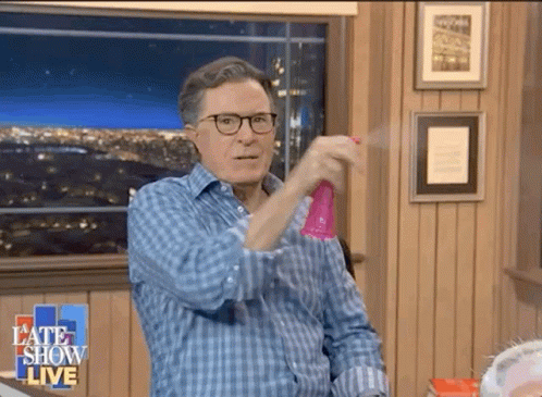A Man Wearing Glasses Is Spraying Something With A Spray Bottle On A Late Show Live Show GIF