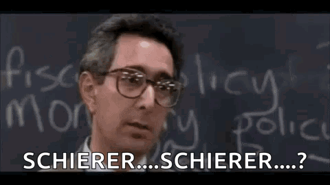 A Man Wearing Glasses Is Standing In Front Of A Blackboard With Chalk Writing On It . GIF