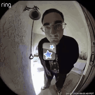 A Man Wearing Glasses Is Standing In Front Of A Door With A Ring Doorbell . GIF