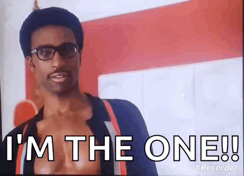 A Man Wearing Glasses Is Standing In Front Of A Red Wall And Says `` I 'M The One ! '' GIF