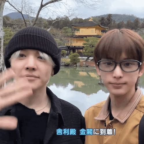 A Man Wearing Glasses Is Standing Next To Another Man Wearing A Beanie GIF