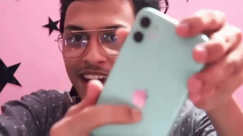 A Man Wearing Glasses Is Taking A Selfie With A Blue Iphone . GIF
