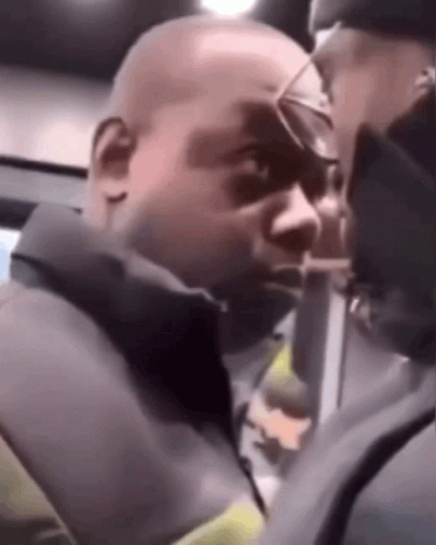 A Man Wearing Glasses Is Talking To Another Man In A Dark Room . GIF