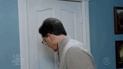 A Man Wearing Glasses Looks Through A Door That Says Late Show On It GIF