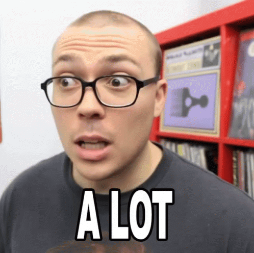 A Man Wearing Glasses Says A Lot In Front Of A Bookshelf GIF