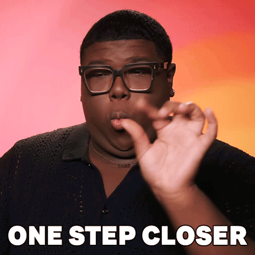 A Man Wearing Glasses Says One Step Closer With His Hand GIF