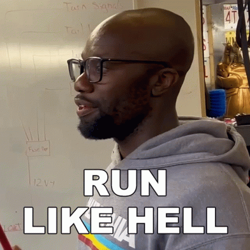 A Man Wearing Glasses Says Run Like Hell In Front Of A White Board GIF