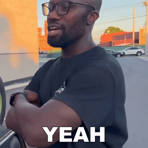 A Man Wearing Glasses Says Yeah While Standing In Front Of A Car GIF
